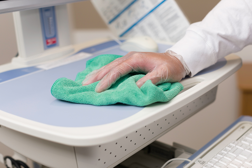 Close-up of hand with a glove on and microfiber wiping down a table
